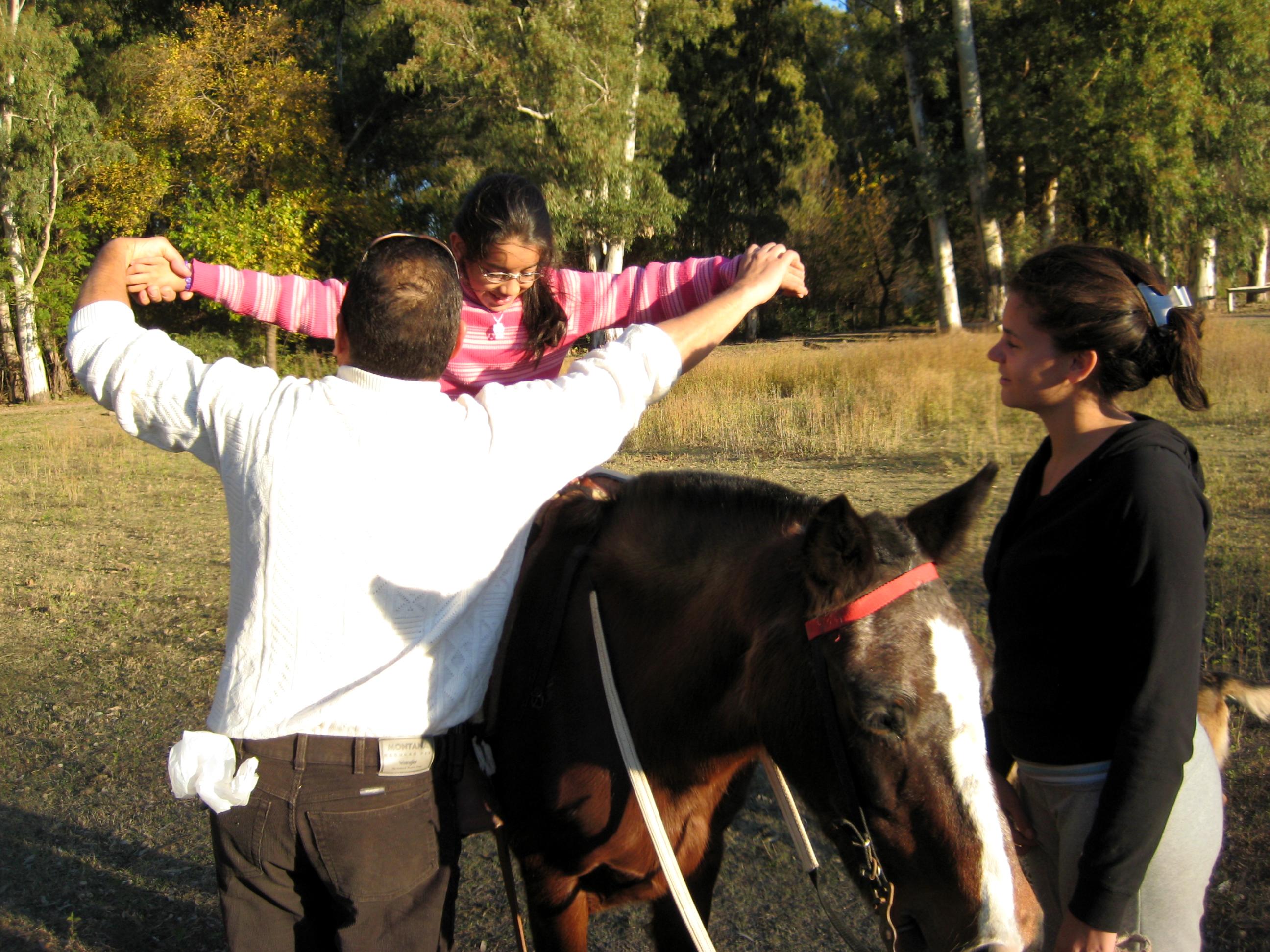 Projects Abroad Equine Therapy interns working with children and horses in Argentina help a child ride a horse. Equine Therapy interns help a young child ride a horse during a therapy session at a centre in Argentina.